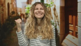 Woman holds hand while pointing into an alley as her blonde young smile reflects windblown hair and striped casual outfit. - Powered by Shutterstock - Get 15% off with code: PIKWIZARD15