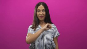 Woman brunette young hispanic fist forward to camera in pink studio wearing striped top and bracelet; confidence empowerment. - Powered by Shutterstock - Get 15% off with code: PIKWIZARD15