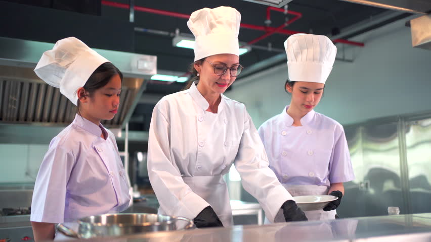 Group of culinary students and professional chefs in white uniforms and hats in a modern cooking school kitchen. Learning cooking, frying, cook a spaghetti in professional kitchen with instructor. - Powered by Shutterstock - Get 15% off with code: PIKWIZARD15