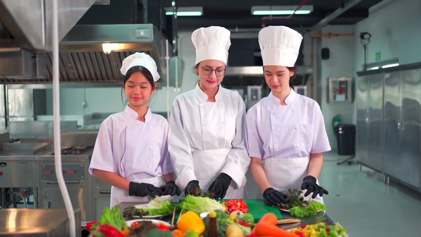 Group of culinary students and professional chefs in white uniforms and hats standing together in a modern cooking school kitchen, smiling confidently at the camera showing teamwork and hospitality. - Powered by Shutterstock - Get 15% off with code: PIKWIZARD15