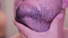 Close-up footage of a man examining his stubble with his hands before shaving. - Powered by Shutterstock - Get 15% off with code: PIKWIZARD15