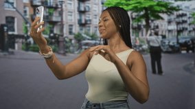 Woman holding smartphone and tapping screen on a city street while smiling and looking down; calm focus connection. - Powered by Shutterstock - Get 15% off with code: PIKWIZARD15