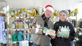 Elderly couple chooses holiday kits of care products in a supermarket decorated for Christmas. Wife and husband in a Santa hat doing New Year's shopping in a household store - Powered by Shutterstock - Get 15% off with code: PIKWIZARD15