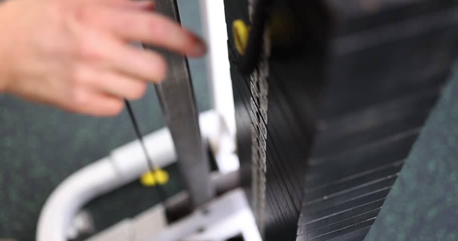 A dedicated person adjusts weights on a gym machine, showing their commitment to fitness and daily exercise