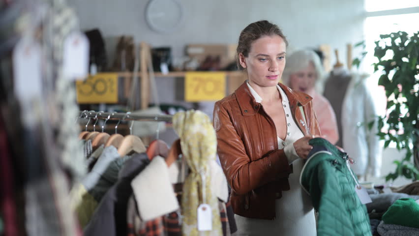 During November sales, woman choose and buy down coat, choose some wardrobe items. Discount season, promotional offers. Chain store of affordable clothing 