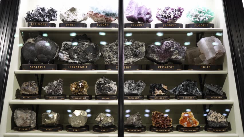 Minerals antimonite pyrite fluorite sphalerite tetrahedrite and galenite displayed in illuminated museum case geological collection showing metallic crystals vivid textures and natural formations