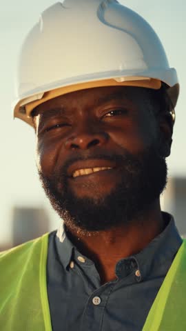 Vertical portrait of professional engineer or architect looking at camera, african american male person with white hard hat. Closeup of face of black man, safety and protection in construction site