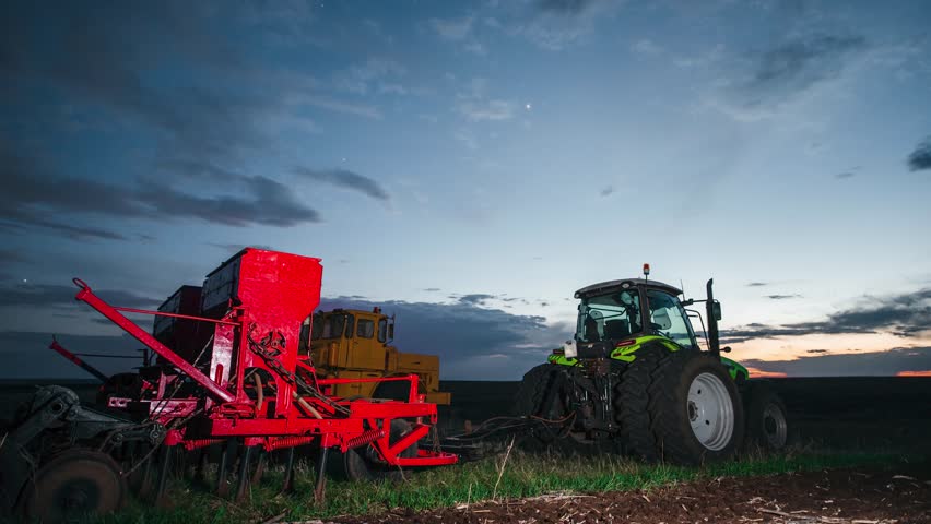 sunset in a field above a tractor with a seed drill, time-lapse of fast-moving clouds in the night sky
