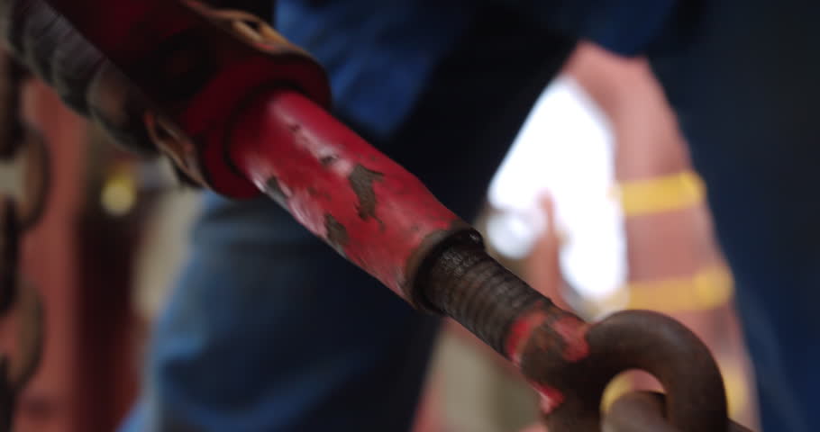Laborer screws connecting heavy chain on cargo ship desk closeup. Skilled sailor attaches heavy metal anchor during vessel mooring at dock