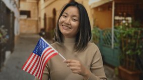 Woman with asian descent holding american flag on city street smiling outdoors in usa, representing cultural diversity and patriotism in urban setting. - Powered by Shutterstock - Get 15% off with code: PIKWIZARD15