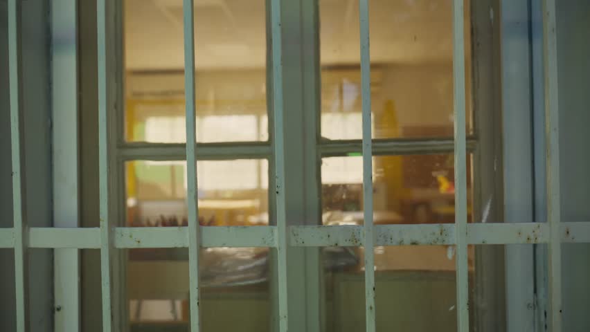 School window, looking into an empty classroom. Slow dolly-in move toward window. Calm, vacant scene education, school closure, safety, lockdowns, truancy, or investigations. No people. sad, lonely