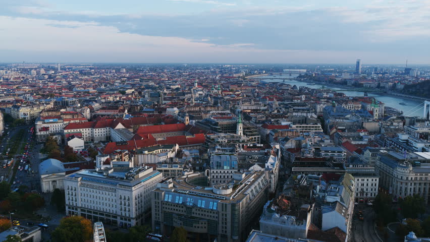 Panoramic view of central Budapest with the Danube River and iconic rooftops stretching across the skyline under soft evening light.