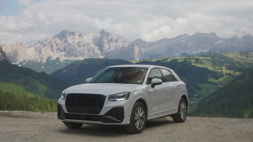 Man getting out of a white car at Gardena Pass in the Dolomites, Italy. Tourist enjoying panoramic mountain landscape and scenic alpine road travel experience