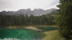 Cinematic view of Lago di Carezza alpine lake in the Dolomites, Italy, surrounded by pine forest and mountain peaks reflecting in the turquoise water  - Powered by Shutterstock - Get 15% off with code: PIKWIZARD15