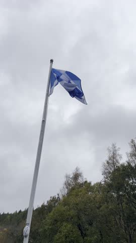 Looking up at a Scottish Saltire flag, the national flag of Scotland. The flag is on a white flag pole.