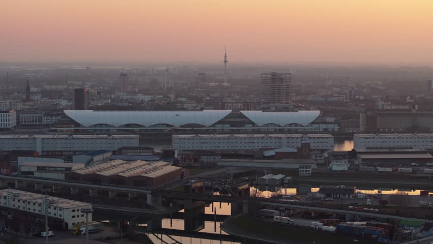 Urban landscape of Mannheim, Germany, from a high angle perspective at dusk. Central train station and city buildings under a warm, hazy sky