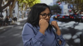 Woman wearing glasses and blue shirt with raised fists in boxing stance on city street crosswalk; confidence empowerment strength. - Powered by Shutterstock - Get 15% off with code: PIKWIZARD15