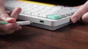 Hands connect a white USB-C cable to a sleek mechanical keyboard, emphasizing essential device power, data transfer, and preparation for productive digital work or gaming - Powered by Shutterstock - Get 15% off with code: PIKWIZARD15