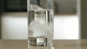 Effervescent tablet falls into a glass of water, close up. Pill dissolving, kitchen on background - Powered by Shutterstock - Get 15% off with code: PIKWIZARD15