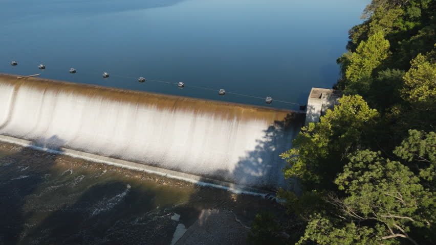 Drone glides along Spavinaw Spillway, wide curved dam and water flowing down, Oklahoma, USA