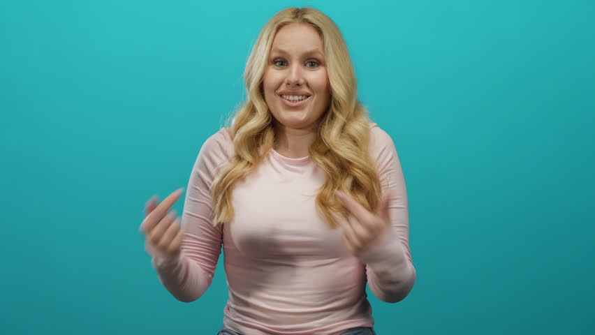 Woman smiling confidently with long blonde hair and a casual pink top against a vibrant blue background, expressing joy and positivity.