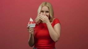 Woman laughing while holding ice cream with strawberries against a vibrant red background, wearing a red shirt and displaying joy. - Powered by Shutterstock - Get 15% off with code: PIKWIZARD15