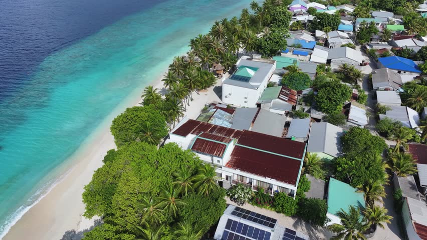 Aerial view of the contrasting blues of the ocean and the whites of the sandy beach near buildings, Maalhos, Baa Atoll, Maldives.