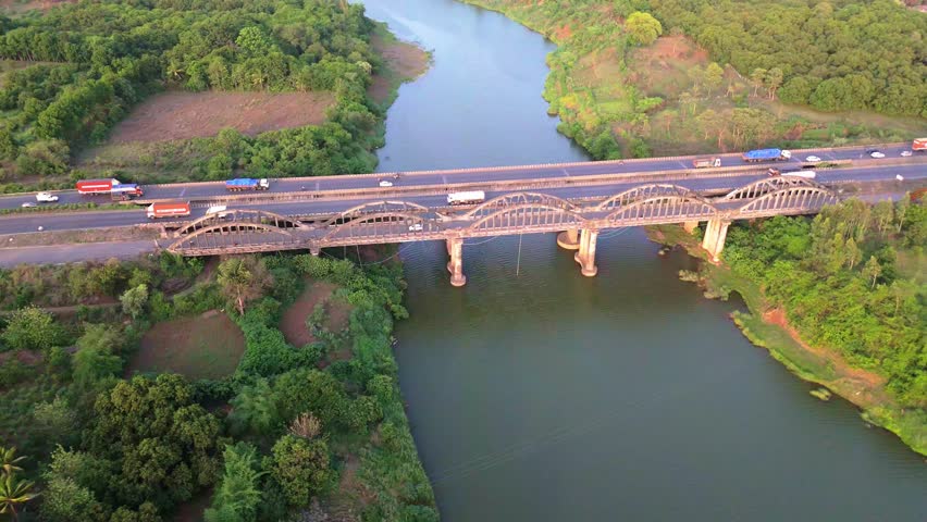 Aerial View Expressway Bridge Over River in Lush Greenery, Drone Shot landscape blends with infrastructure, Calm Waters Flow Beneath Concrete Viaduct, Traffic Passes Above riverbed, Highway connects