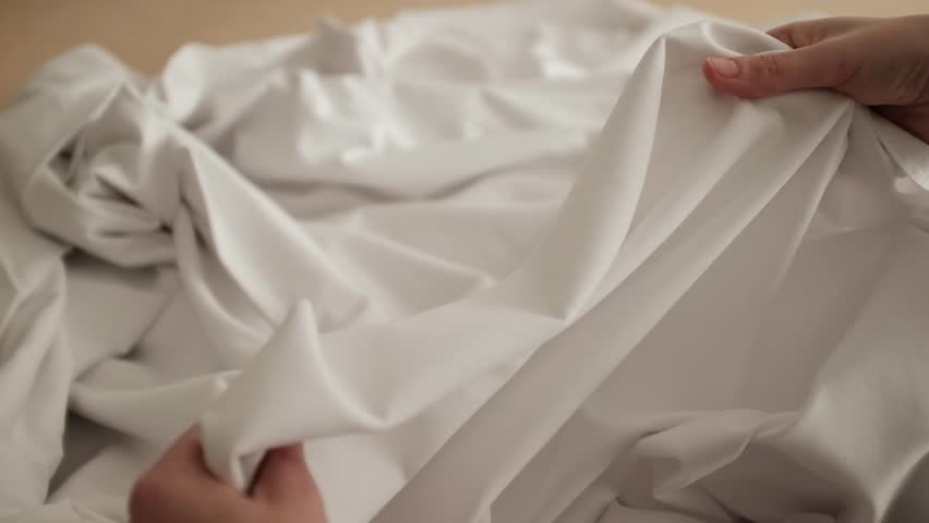Closeup slow motion video of white knitwear stretching elastic fabric for t-shirts. Appreciating pleasant texture of high quality textile for clothes. Soft and cosy textile. Expensive fabric.