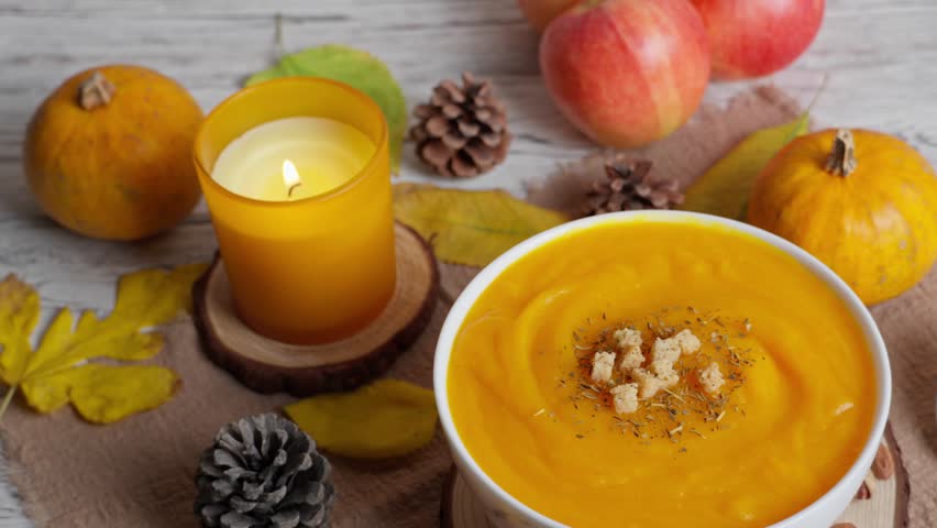 Warm pumpkin soup with croutons, autumn leaves, pumpkins, apples, and a flickering candle creating a festive seasonal mood - Powered by Shutterstock - Get 15% off with code: PIKWIZARD15