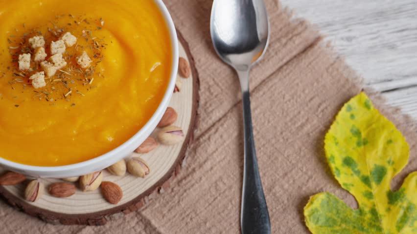 Warm pumpkin soup with croutons, autumn leaves, pumpkins, apples, and a flickering candle creating a festive seasonal mood - Powered by Shutterstock - Get 15% off with code: PIKWIZARD15