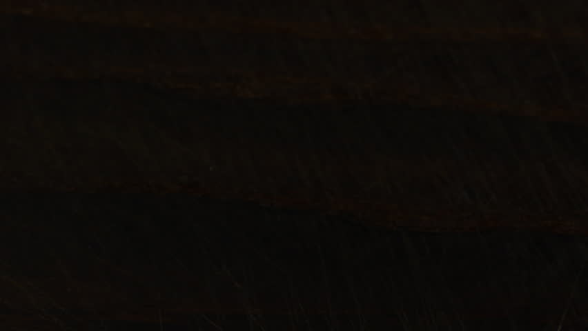 White sugar crystals are sprinkled onto a dark brown wooden surface. A big pile of sugar, a lot of sugar.