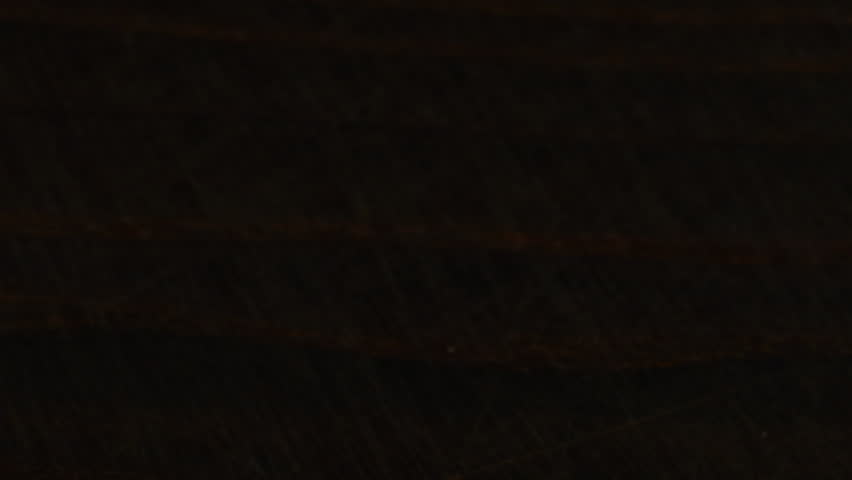 White sugar crystals are sprinkled onto a dark brown wooden surface. A big pile of sugar, a lot of sugar.