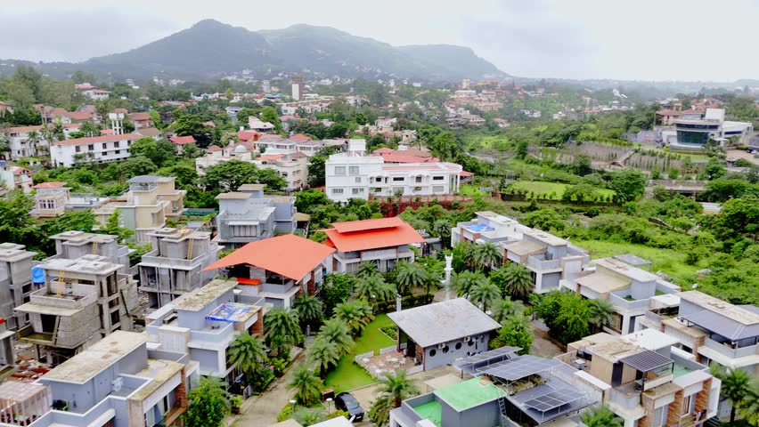 Drone view small town aligned with leafy roads, Aerial shot reveals modern dwellings by thick trees, Cottages line the edge of green valleys, Clustered chalet appear between rolling grasslands, Villas