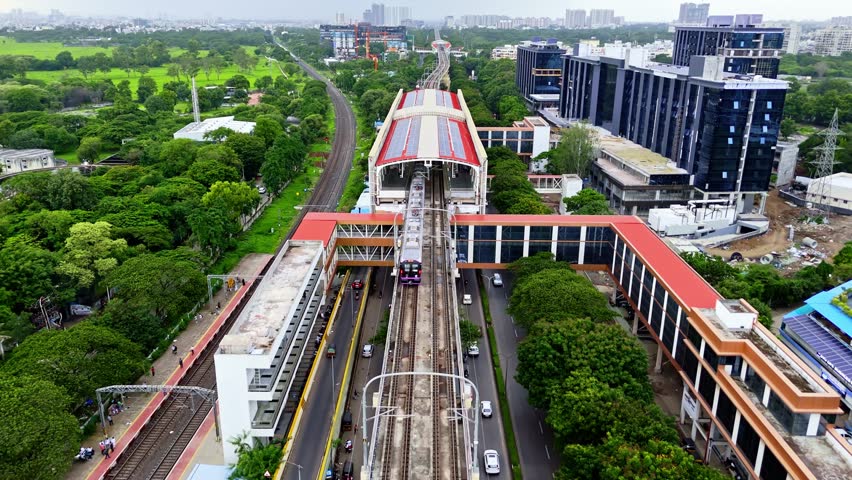 Aerial View Metro City Train Moving Along Elevated Bridge, Drone Shot Vehicles Flowing Across Busy Expressway Flyovers, Railway Lines Pass Through Leafy Environment, Pune Rail Near Corporate Complex