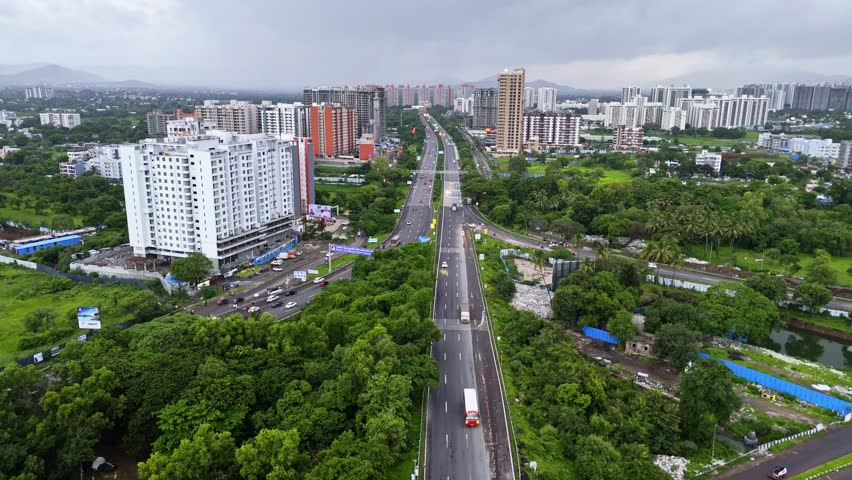 Aerial view road network linking foliage and skyscrapers, Drone footage captures vehicle moving across city expressways, Main highway cuts by busy metropolitan core, Downtown hub with freeway traffic