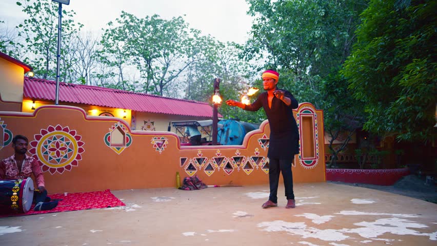 Traditional Dancer Displays Fiery Art by Open Village, Folk Fire Performer Twirls Flames dancing in Rural area, Cultural male with colorful turban on countryside stage, Man artist amazes local crowd