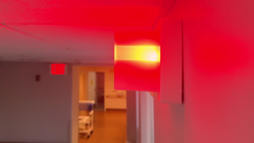Bright red indicator light flashes in a hospital or nursing home hallway, signaling an emergency or patient alert. Looping. 14931  	