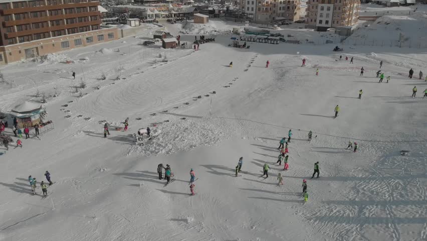 Skiers and families having fun on a lively snowy mountain resort where the sun shines warmly and everyone embraces the joyful winter spirit