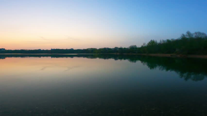 Peaceful lake panorama reflecting colorful sunset skies during twilight