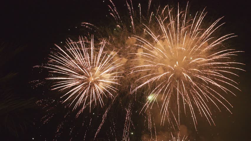 The night sky bursts with vibrant fireworks, illuminating the landscape. Brilliant colors explode in patterns, captivating viewers. The atmosphere buzzes with excitement during the festive event.