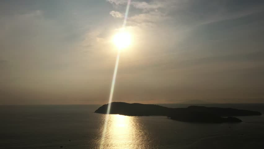 Stunning sunset over serene sea waves near Langkawi Island, reflecting golden light on a quiet coastline in the late evening in a tropical paradise