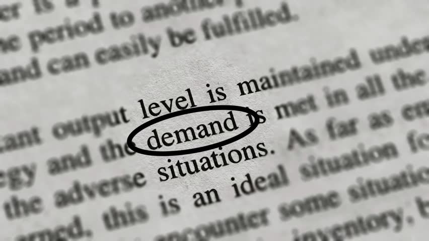 Closeup of demand word or text printed on news articles, books or magazine white pages emphasize and highlight with background blur. Extreme closeup macro top view.