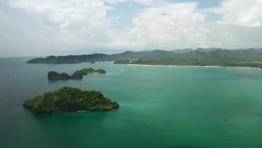 Tropical islands overgrown with jungle in Kilim Park on Langkawi Island, surrounded by clear blue waters. Malaysia