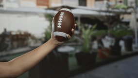 Man holding a football on a city street with blurred urban background, showcasing outdoor sports and caucasian ethnicity - Powered by Shutterstock - Get 15% off with code: PIKWIZARD15