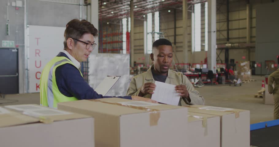 Warehouse supervisor using laptop launching data overlay, associate scanning barcodes for inventory. Logistics, technology, digital, organization, industrial, efficiency, teamwork