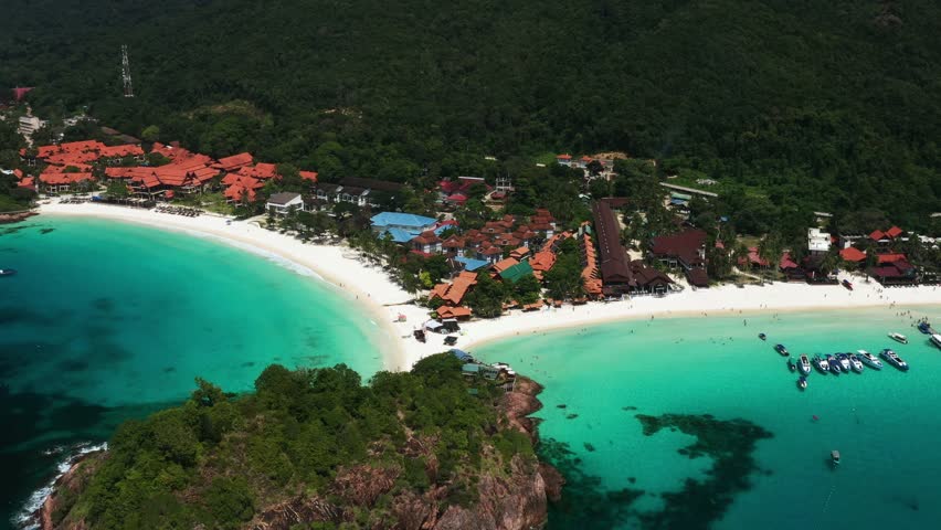 Aerial view of the tropical long beach of Redang Island with clear turquoise waters and lush green hills on a sunny day. Malaysia