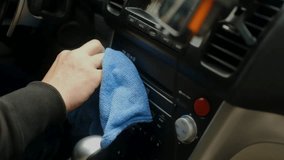A hand wipes the gear shift console with a blue microfiber cloth inside a car. - Powered by Shutterstock - Get 15% off with code: PIKWIZARD15