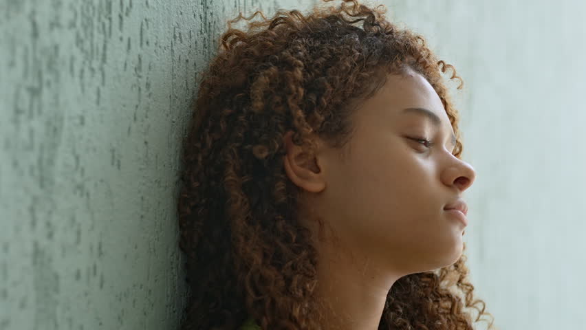 Teenage Girl Leaning On Wall With Relaxed Smile And Eyes Closed, Enjoying Moment Of Peace And Happiness In Quiet Indoor Setting
