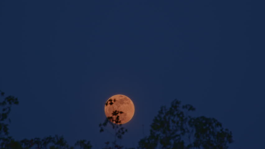 a blood moon glowing in deep orange hues, partially veiled by wisps of dark clouds. This atmospheric celestial scene captures the mysterious and dramatic beauty of the lunar surface.
